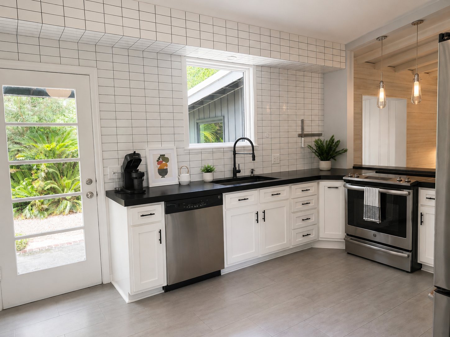 Kitchen with white cabinetry, black countertops, tile backsplash, and stainless appliances